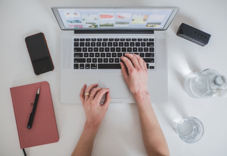 Business Blogging - someone writing a blog on a laptop with mobile phone and notebooks on desk