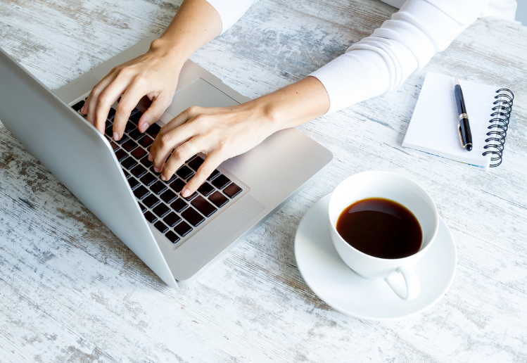 technical SEO freelancer typing on a keyboard with a coffee and pen and paper